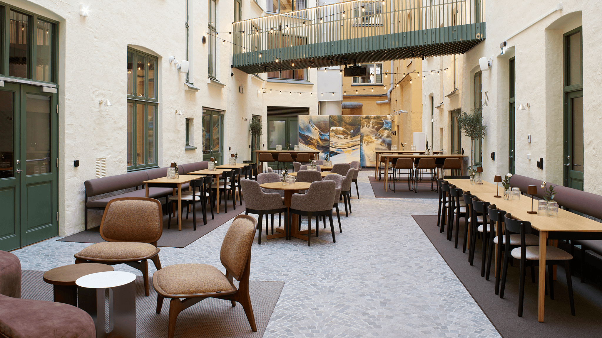Eidra's Oslo office courtyard with mixed seating, string lights, and a large artwork backdrop.